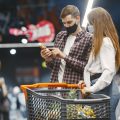 Covid-19 spreading outbreak. Couple in medical protective mask. Family walks in a supermarket.