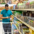 Focused African American man reading shopping list on smartphone. Responsible bearded guy buying food according to list. Shopping concept