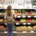 Good looking woman standing in front of vegetable shelves choosing what to buy.