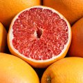 Close up of juicy halved orange lying near delicious fresh oranges at a fruit stall. Ripe fruit background