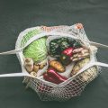 Various vegetables in eco friendly mesh bags on dark background. Top view. Zero waste concept. No plastic lifestyle