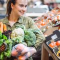 Woman in the supermarket. Beautiful young woman shopping in a supermarket and buying fresh organic vegetables. The concept of healthy eating. Harvest